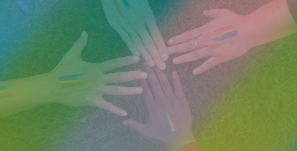 Fyra händer med regnbågsflaggor målade på händerna sträcker sig mot mitten av bilden.